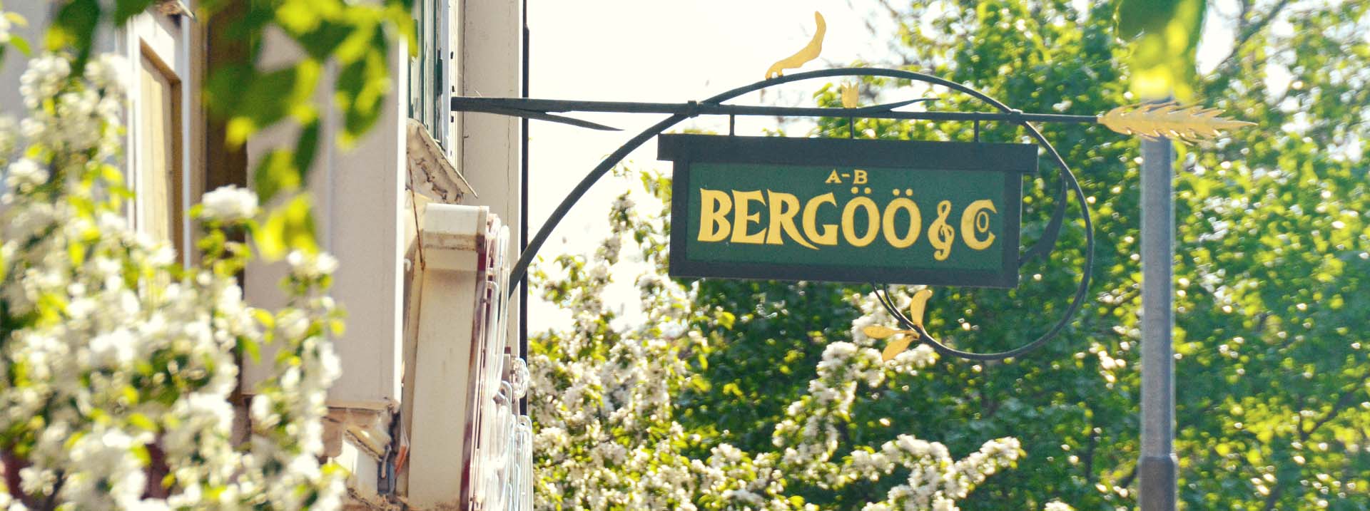 Bergöös fasadskylt och blommande träd